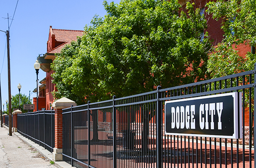 Platform of the train station with a retro style sign attached to the fence in Dodge City, KS